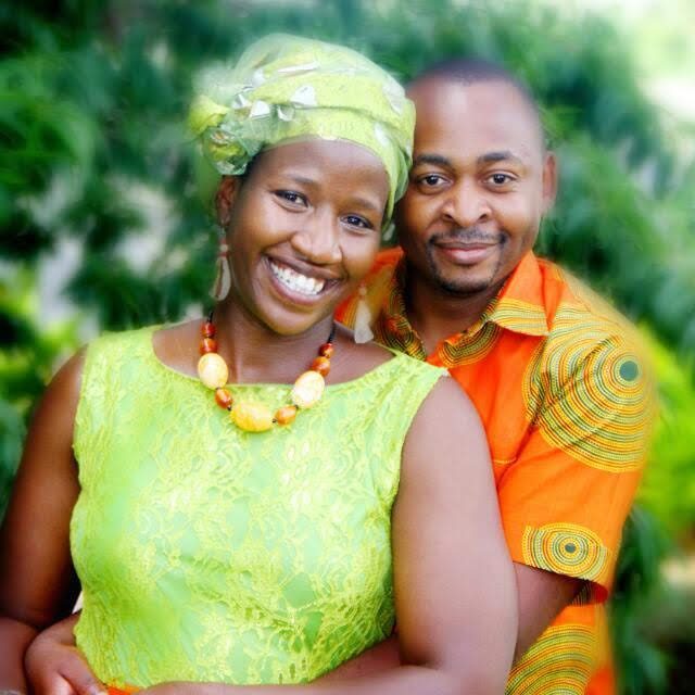 Manka and Brian in bright green and orange, smiling in a garden.