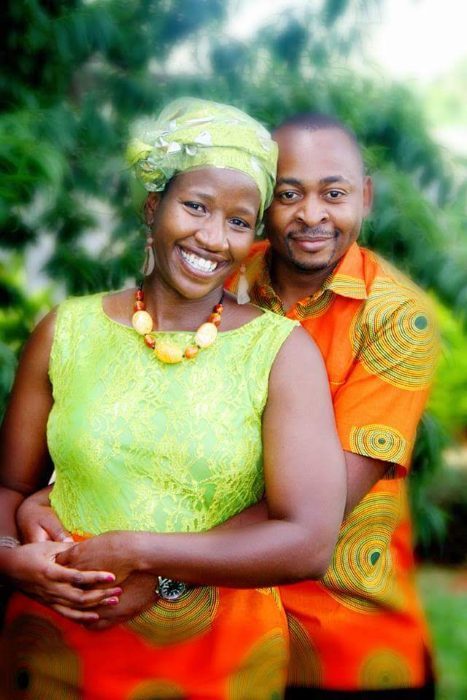 Brian and Manka smiling together in bright green and orange outfits.